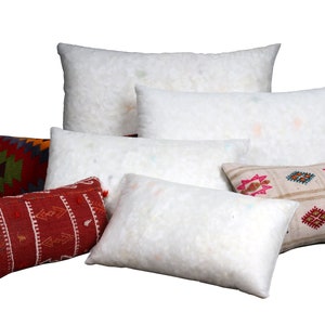 May include: A collection of decorative pillows and pillow inserts. The pillows feature various patterns and colors, including red, green, and beige. The inserts are white and fluffy, providing a soft contrast to the patterned pillow covers.