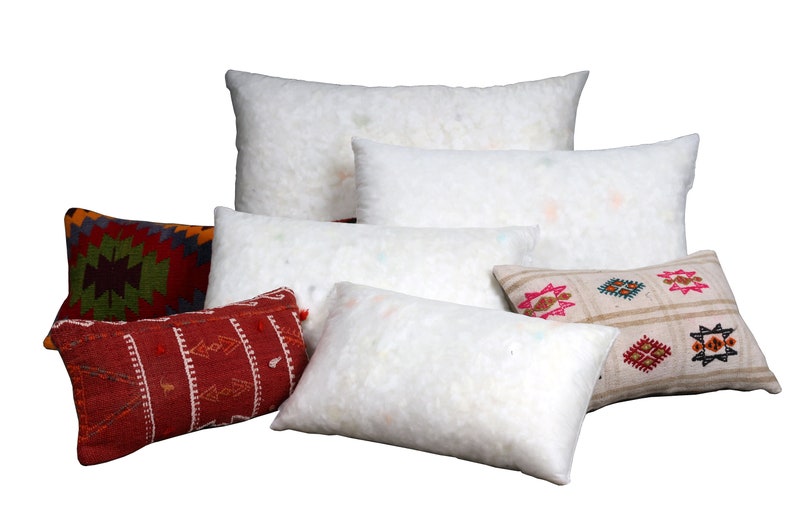 May include: A collection of decorative pillows and pillow inserts. The pillows feature various patterns and colors, including red, green, and beige. The inserts are white and fluffy, providing a soft contrast to the patterned pillow covers.