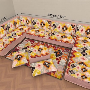 Könnte beinhalten: Ein Ecksofa mit einem farbenfrohen geometrischen Muster in Gelb, Rot und Schwarz. Das Sofa ist 330 cm lang, 190 cm breit und 70 cm tief. Inklusive passender Kissen und einem Teppich mit dem gleichen Muster.