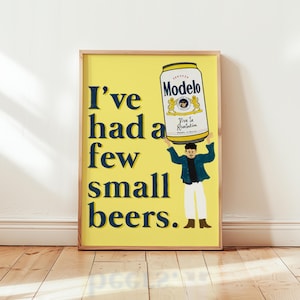 May include: A framed art print with a yellow background and the text "I've had a few small beers." A cartoon illustration depicts a person holding a Modelo beer can above their head. The beer can has a white and gold label.