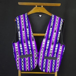 Peut inclure: Un gilet à rayures violettes, noires et blanches avec un col en V et des boutons noirs. Le gilet a deux poches noires avec rabats.