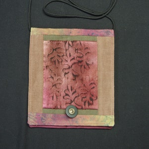 Peut inclure: Un petit sac à main rectangulaire en tissu avec un motif floral brun, vert et rose. Le sac a une bandoulière noire et une fermeture à bouton noir.