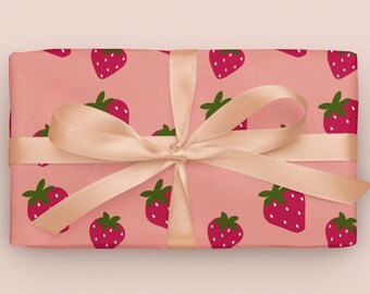May include: A pink gift box with a peach-colored satin ribbon tied in a bow. The box is wrapped in paper with a repeating pattern of red strawberries on a pink background.