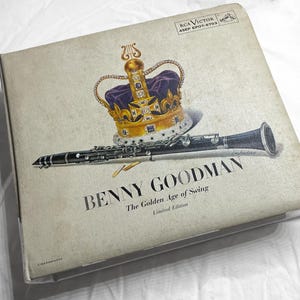 May include: Vintage album cover featuring a gold and purple crown and a black clarinet. The album is titled "BENNY GOODMAN The Golden Age of Swing" and is a limited edition. The cover has a faded, aged appearance.