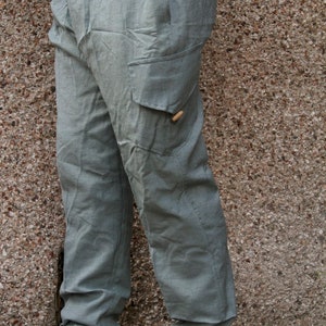 May include: A pair of light grey cargo trousers with a button on the side pocket.