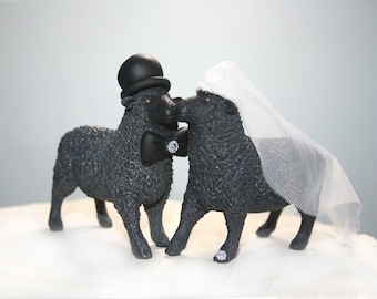 Può includere: Topper per torta nuziale a forma di pecore nere, lo sposo indossa un cappello a cilindro e un papillon, la sposa indossa un velo.