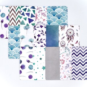 Peut inclure: Un ensemble de 12 papiers num&eacute;riques avec diff&eacute;rents motifs, y compris des formes g&eacute;om&eacute;triques, des motifs floraux et des attrape-r&ecirc;ves. Les motifs sont dans des tons de bleu, violet, vert et gris.