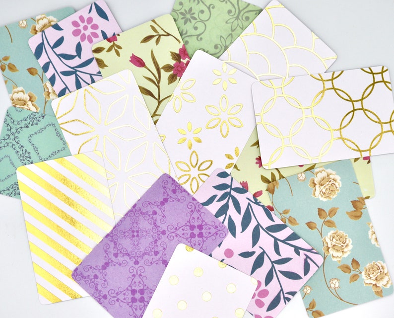 Peut inclure: Un ensemble de cartes d&eacute;coratives avec diff&eacute;rents motifs et des accents dor&eacute;s. Les cartes pr&eacute;sentent des motifs floraux, des formes g&eacute;om&eacute;triques et des rayures.