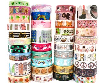 May include: A collection of four stacks of decorative washi tape rolls featuring various patterns including birthday text, rainbows, cats, dogs, buildings, makeup, peace signs, and stars. The rolls display colourful illustrations, graphic prints, and repeating motifs in a variety of styles and colours.