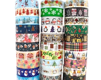 May include: Three vertical stacks of decorative washi tape rolls featuring various Christmas-themed patterns including snowmen, penguins, pine trees, poinsettias, plaid, gift boxes, and the word JOY in gold foil lettering on a white background.