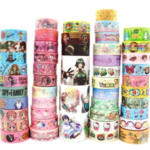 Puede incluir: Una colección de varios rollos de cinta decorativa washi apilados en cinco columnas verticales. Las cintas presentan diversas ilustraciones coloridas de personajes de anime y dibujos animados, patrones y texto, incluyendo Spy Family, Hello Kitty y Gudetama.