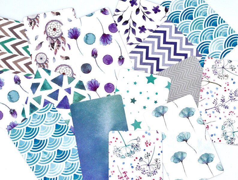 Peut inclure: Un ensemble de 12 cartes &agrave; motifs pr&eacute;sentant divers designs, notamment des attrape-r&ecirc;ves, des fleurs, des formes g&eacute;om&eacute;triques et des &eacute;toiles. Les cartes sont imprim&eacute;es sur du papier blanc avec des motifs de type aquarelle dans des tons de bleu, vert, violet et gris.