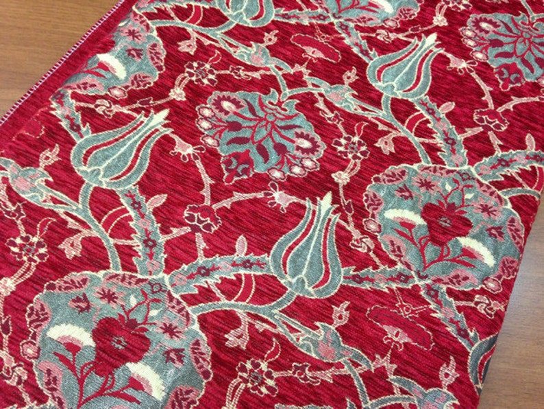 May include: Red fabric with a repeating pattern of stylized flowers and leaves in shades of gray and cream.