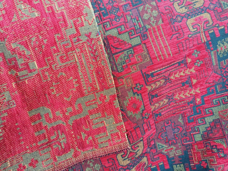 May include: Close-up of a red and gold patterned fabric with a geometric design. The fabric has a woven texture and a slightly raised pattern.