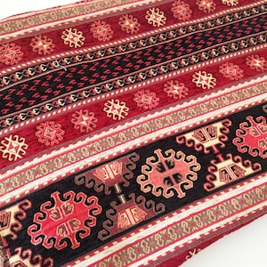 Puede incluir: Tela estampada en rojo, negro y crema con un dise&ntilde;o geom&eacute;trico. La tela tiene una textura tejida y est&aacute; hecha de un material suave y c&oacute;modo.