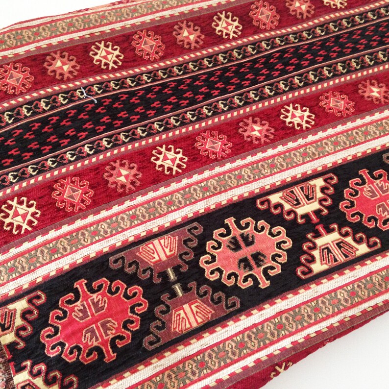 Puede incluir: Tela estampada en rojo, negro y crema con un dise&ntilde;o geom&eacute;trico. La tela tiene una textura tejida y est&aacute; hecha de un material suave y c&oacute;modo.