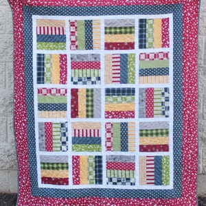 May include: A patchwork quilt with a red, white, and blue color scheme. The quilt is made up of squares of different fabrics, each with a different pattern. The quilt is bordered with a red fabric with white polka dots.