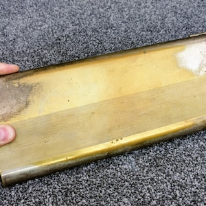 May include: A gold-colored metal cigarette case with a textured surface and a slightly worn finish.