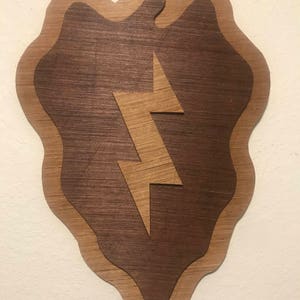 May include: A wooden wall plaque in the shape of a lightning bolt, with a brown wood background and a lighter brown wood lightning bolt design.