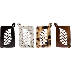 May include: Four hair clips in different patterns. The clips are black, white with black dots, brown with white and black spots, and brown. Each clip has a leaf-shaped design.