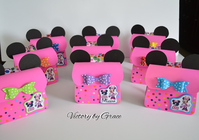 Puede incluir: Cajas de regalo de fiesta de Minnie Mouse en rosa y negro con patrones de lunares, lazos e im&aacute;genes de personajes de Minnie Mouse. Las cajas est&aacute;n decoradas con el n&uacute;mero "2" y el nombre "Mileena".