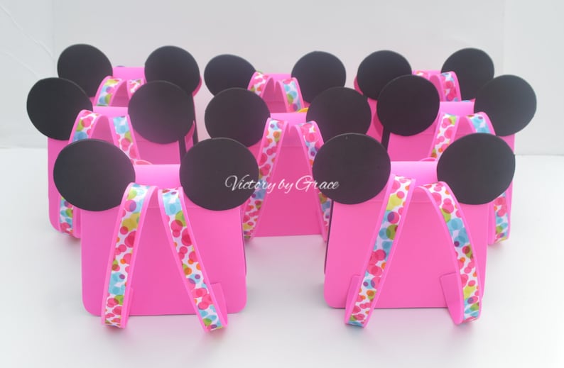 Puede incluir: Cajas de regalo de fiesta rosas con orejas de Mickey Mouse negras y cinta de lunares de colores. Las cajas est&aacute;n decoradas con el texto "Victory by Grace".