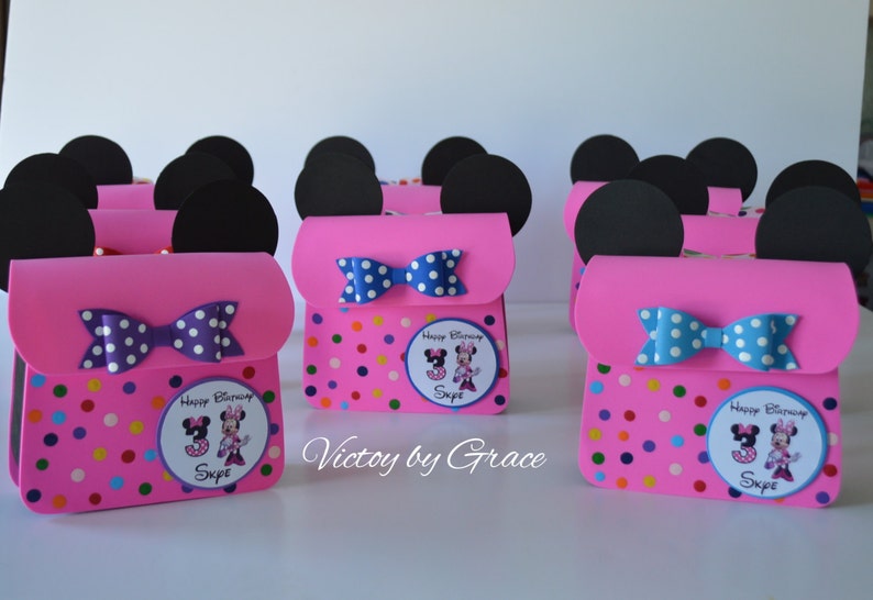 Puede incluir: Bolsas de regalo de fiesta de Minnie Mouse de color rosa y negro con patrones de lunares y un lazo. Cada bolsa tiene una pegatina personalizada con una imagen de Minnie Mouse y el nombre "Skye".