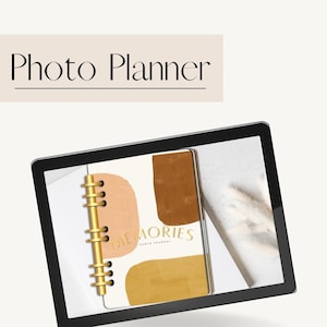 Puede incluir: Una tableta digital que muestra un planificador de fotos con una cubierta blanca y formas abstractas en marrón, naranja y amarillo. El planificador tiene una encuadernación en espiral dorada y el texto "Memories Photo Journal" en la cubierta.