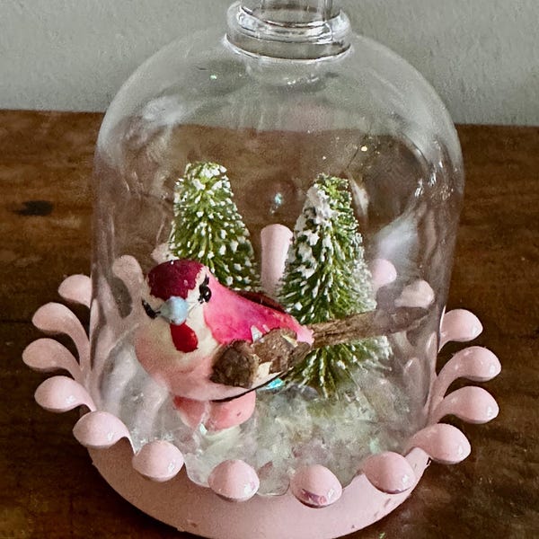A Snow Globe with Bottle Brush Trees - a pink feathered bird - Loose Snow - Plastic Globe with pink bottom