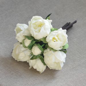 May include: A bouquet of white peonies with green leaves. The peonies are arranged in a cluster and have a soft, delicate appearance.