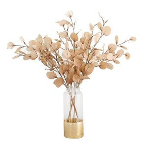 May include: A bouquet of dried eucalyptus branches in a gold-rimmed glass vase.