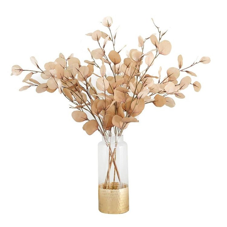 May include: A bouquet of dried eucalyptus branches in a gold-rimmed glass vase.