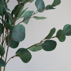 Op de afbeelding: Een bos kunstmatige eucalyptus stengels met groene bladeren. De stengels zijn bruin en hebben een natuurlijke uitstraling.