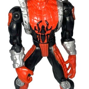 May include: A red and black Spider-Man action figure with white eye lenses. The figure has a spider emblem on the chest and silver accents on the arms and legs. The figure is standing with its legs apart.
