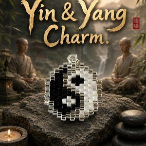 Könnte beinhalten: Ein runder Anhänger mit einem gewebten Perlenmuster in Schwarz und Weiß, das ein Yin-und-Yang-Symbol bildet. Der Anhänger hat eine kleine silberfarbene Metallöse an der Oberseite. Der Text Yin & Yang Charm steht über dem Anhänger.