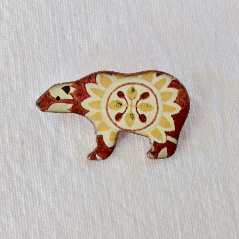 May include: A red and yellow patterned ceramic bear figurine. The bear is standing on all fours and has a stylized design.