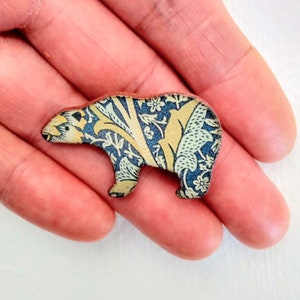 May include: A blue and yellow patterned wooden bear figurine. The bear is standing on its four legs and has a simple design.