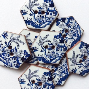 May include: A selection of hexagonal buttons with a blue and white Willow pattern design. Each button features a detailed landscape scene with a pagoda, trees, and figures, and has two holes for sewing. The buttons have a vintage aesthetic.