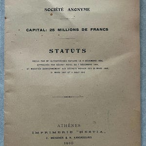 May include: A vintage document with the title "BANQUE D'ORIENT" and the text "SOCI&Eacute;T&Eacute; ANONYME" in black ink. The document is printed on aged, tan paper and includes the text "CAPITAL: 25 MILLIONS DE FRANCS" and "STATUTS". The document is dated 1910.