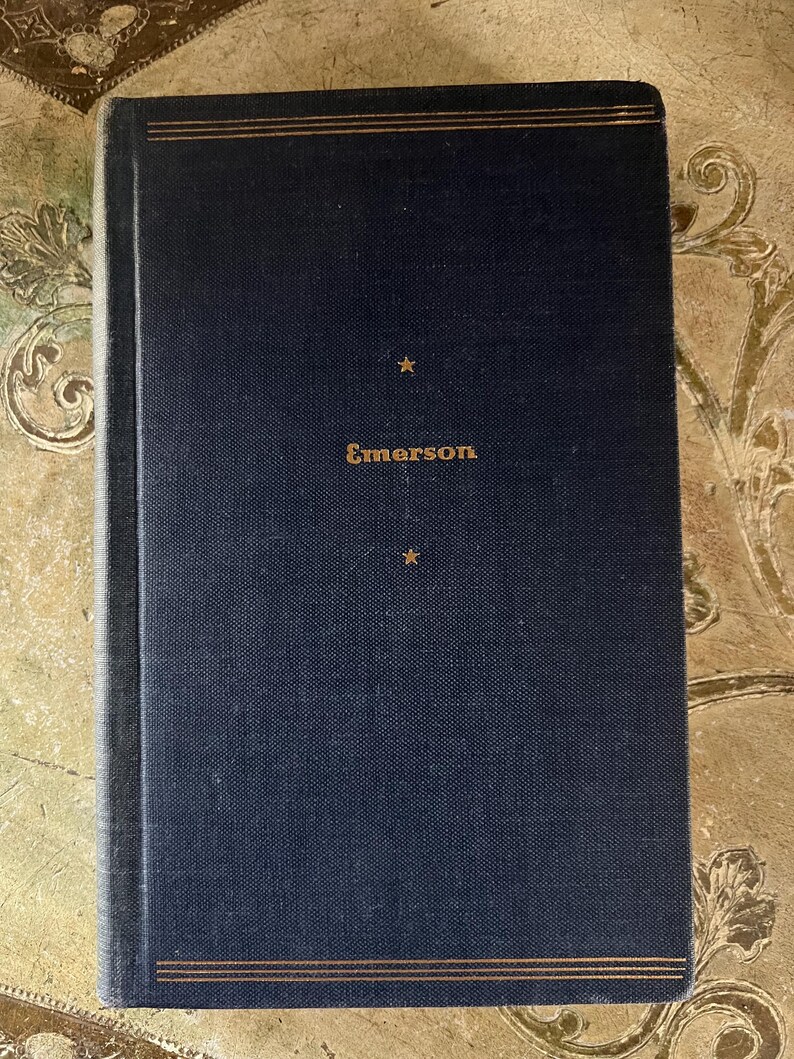 May include: A dark blue hardcover book with gold lettering that reads "Emerson" on the front cover. The book has two gold lines at the top and bottom of the cover.