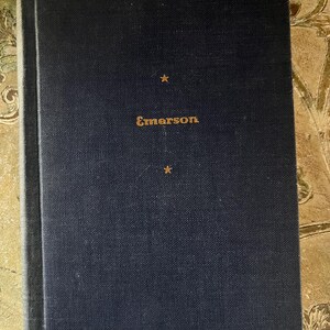 May include: A dark blue hardcover book with gold lettering that reads "Emerson" on the front cover. There are two gold stars on the cover.