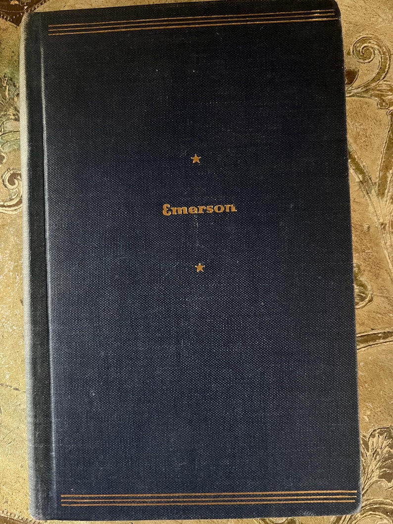 May include: A dark blue hardcover book with gold lettering that reads "Emerson" on the front cover. There are two gold stars on the cover.