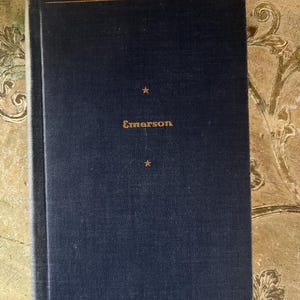 May include: A dark blue hardcover book with gold lettering that reads "Emerson" on the front cover. There are two gold stars above the title.