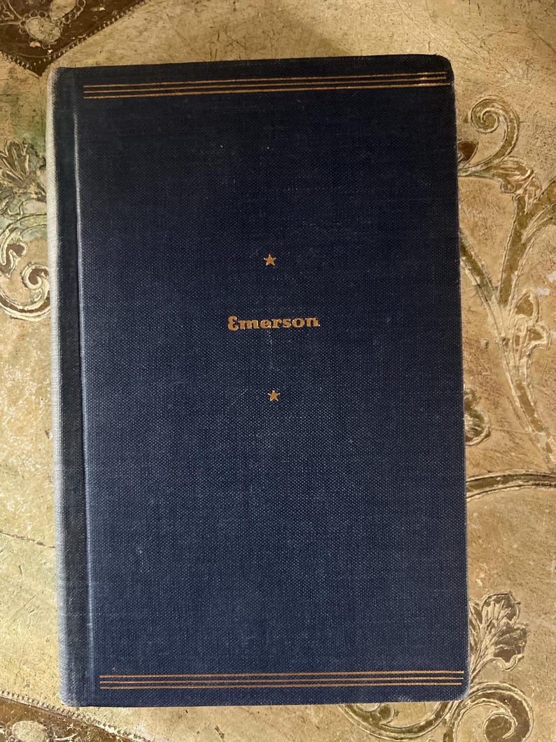 May include: A dark blue hardcover book with gold lettering that reads "Emerson" on the front cover. There are two gold stars above the title.