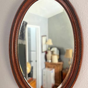 Antique oval Mahogany ornate, beveled oval mirror. Made in Manchester England. 34x24.5x2&quot;. See description.