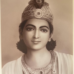 May include: A sepia-toned portrait of a person wearing a crown with a peacock feather and a necklace. The person has dark hair and is looking directly at the viewer.