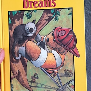 May include: A yellow hardcover book titled Teddy Bear Dreams by Donna Lynne Sava and illustrated by Scott Christian Sava. The cover features a brown teddy bear wearing a red fire chief helmet climbing a ladder toward a small black and white animal.