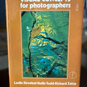 May include: A book titled "VISUAL CONCEPTS for photographers" with a brown cover. The cover features a colorful abstract image with green, blue, and yellow hues. The author's names are listed at the bottom.