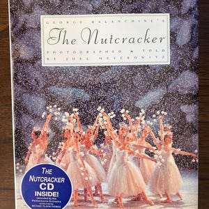 May include: The Nutcracker CD cover featuring a photograph of a ballet performance. The cover has the title "The Nutcracker" and the names George Balanchine, Joel Meyerowitz, and Michael Tilson Thomas. The image shows ballerinas in white dresses.