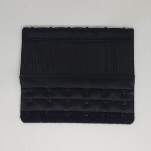 Peut inclure: Un extenseur de soutien-gorge noir avec trois rang&eacute;es de fermetures &agrave; crochet et &oelig;illet. L'extenseur est fait d'un tissu textur&eacute; et a une forme rectangulaire. Les crochets sont de couleur argent.